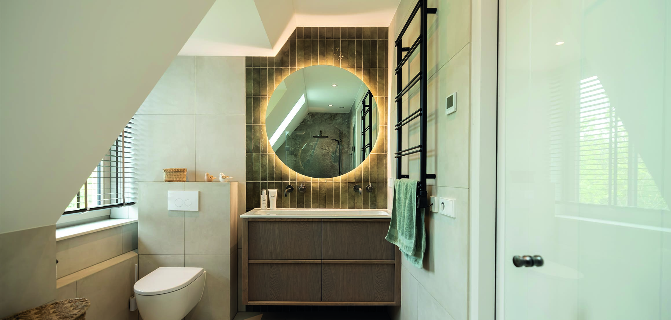 Badkamer met verlichte ronde spiegel in Ouderkerk aan den IJssel