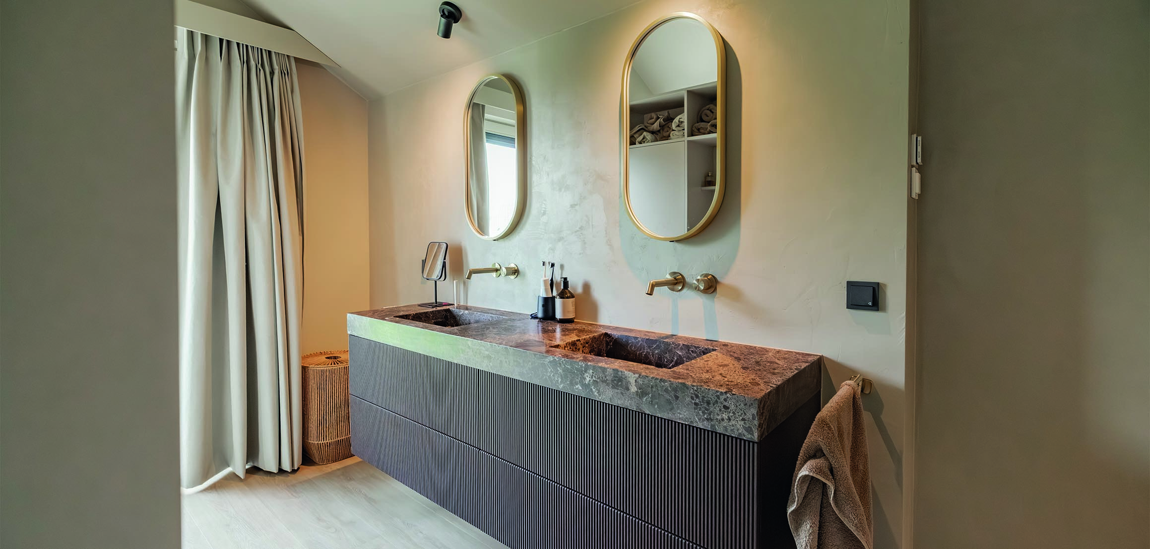 Badkamer met ronde spiegels en natuurstenen wastafel in Heenvliet