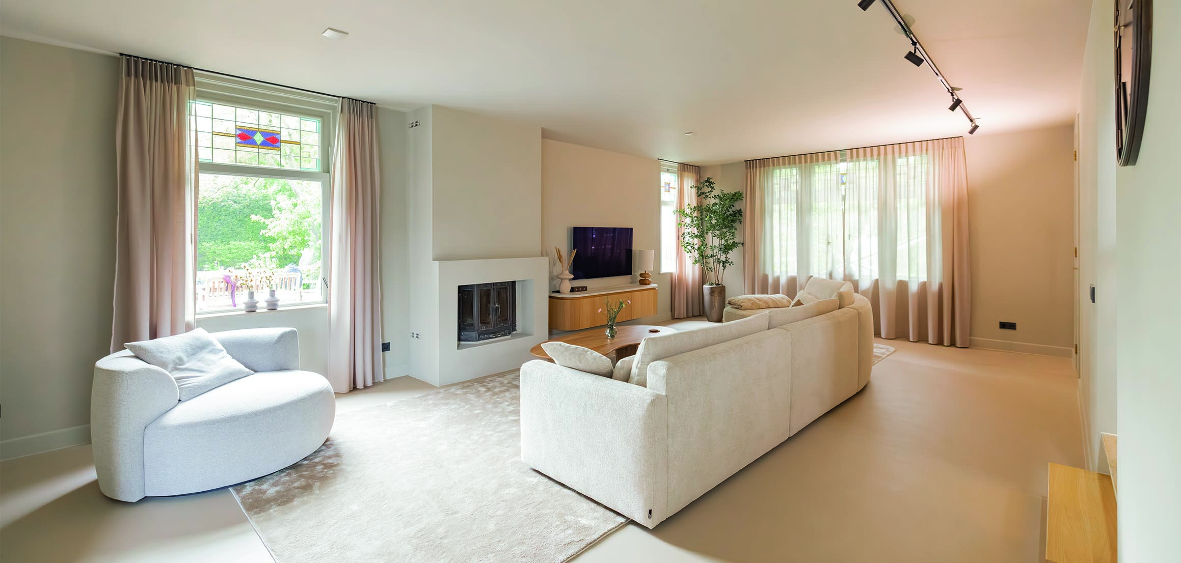 Woonkamer met witte bank en open haard in Heenvliet