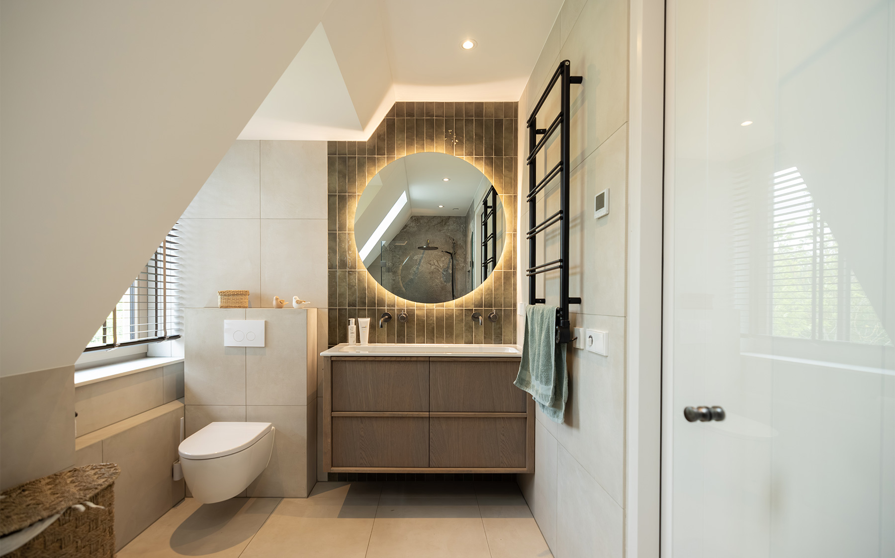 Moderne badkamer met ronde verlichte spiegel en zwevend meubel