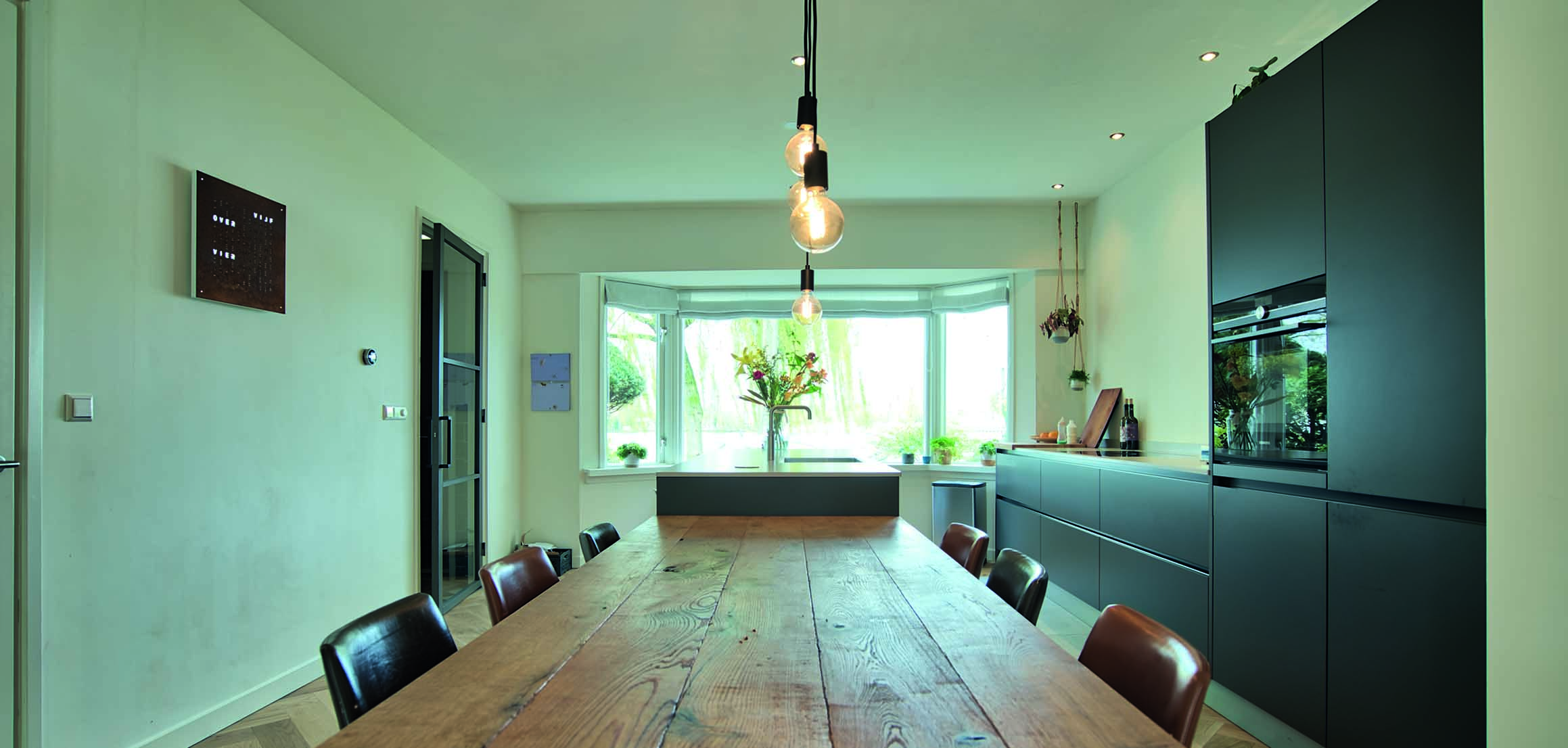 Doorgebroken woonkamer met eettafel en keuken aan de Johan de Wittlaan