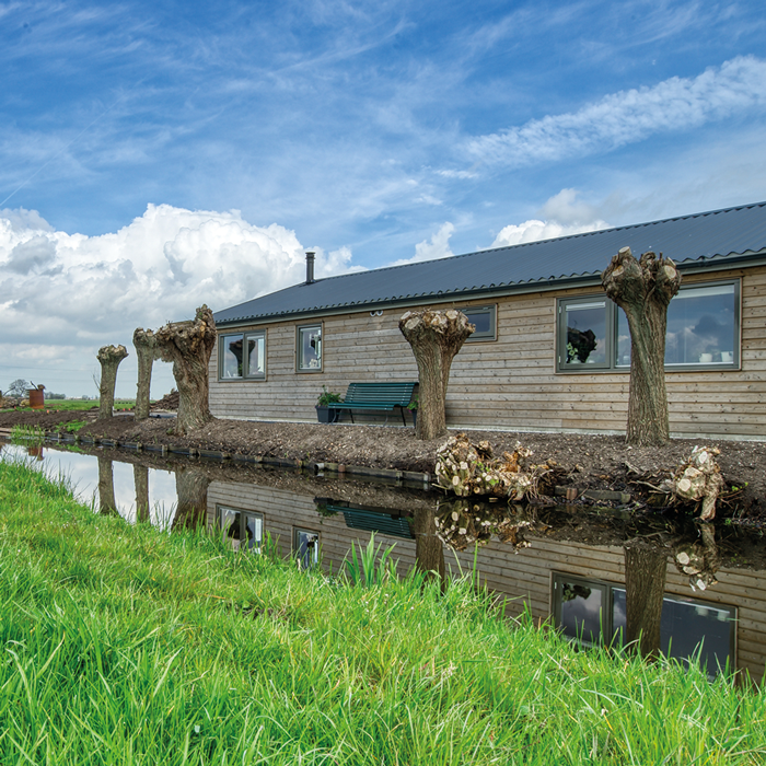 Mantelzorgwoning met houten gevel langs de sloot in de Krimpenerwaard