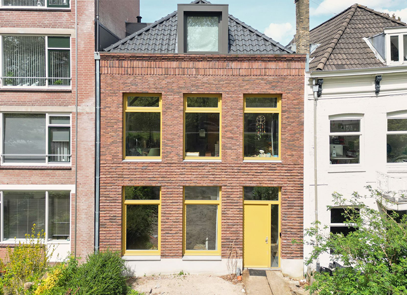 Voorgevel met gele voordeur van nieuwbouwwoning in Rotterdam