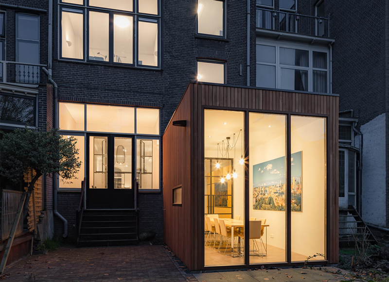 Verlichte aanbouw met glazen pui in de avond in notariskantoor aan de Mathenesserlaan in Rotterdam
