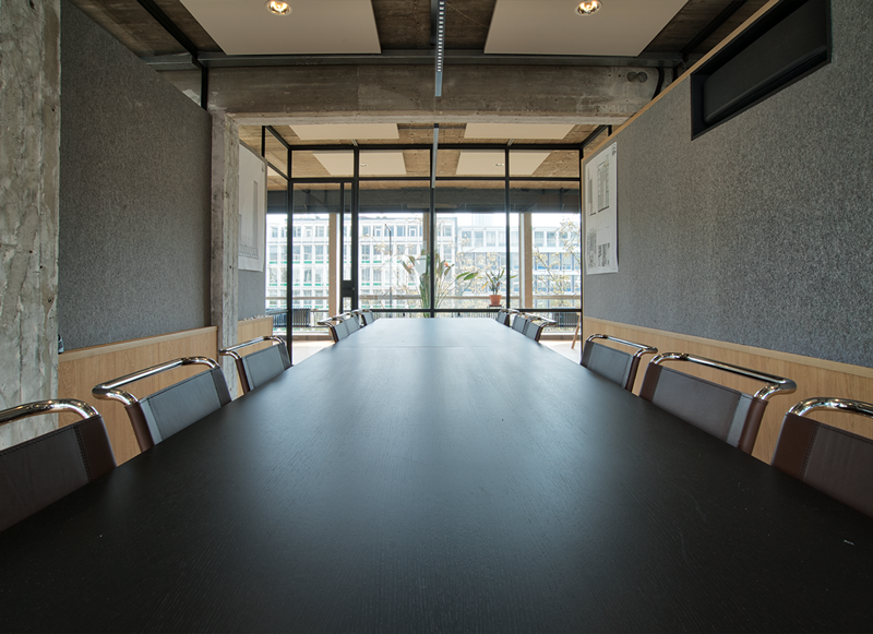 Vergaderzaal met lange zwarte tafel in architectenkantoor De Zwarte Hond in Rotterdam