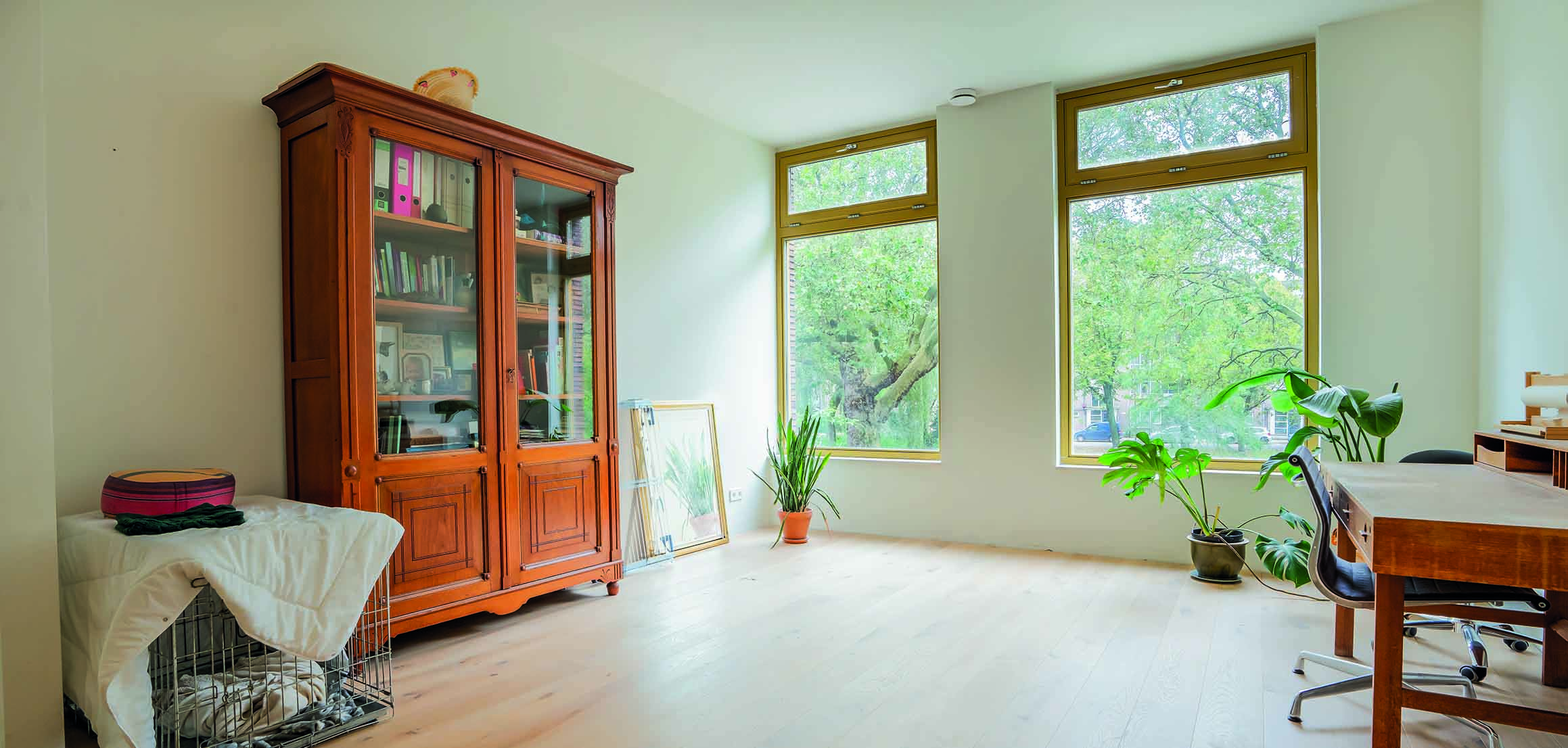Kamer met antieke kast en grote ramen in nieuwbouwwoning in Rotterdam