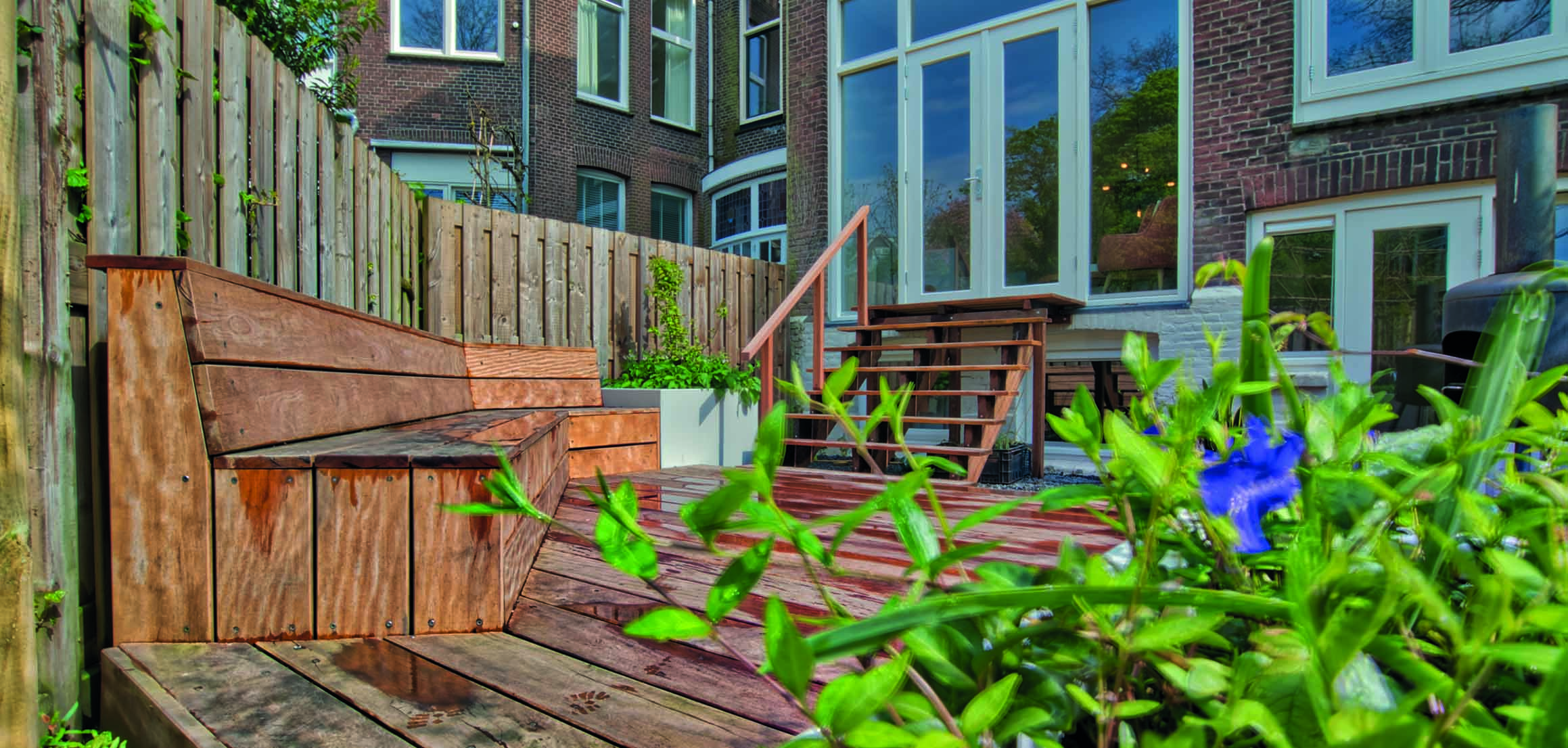 Houten tuinbank en terras achter woning aan de Hooidrift in Rotterdam
