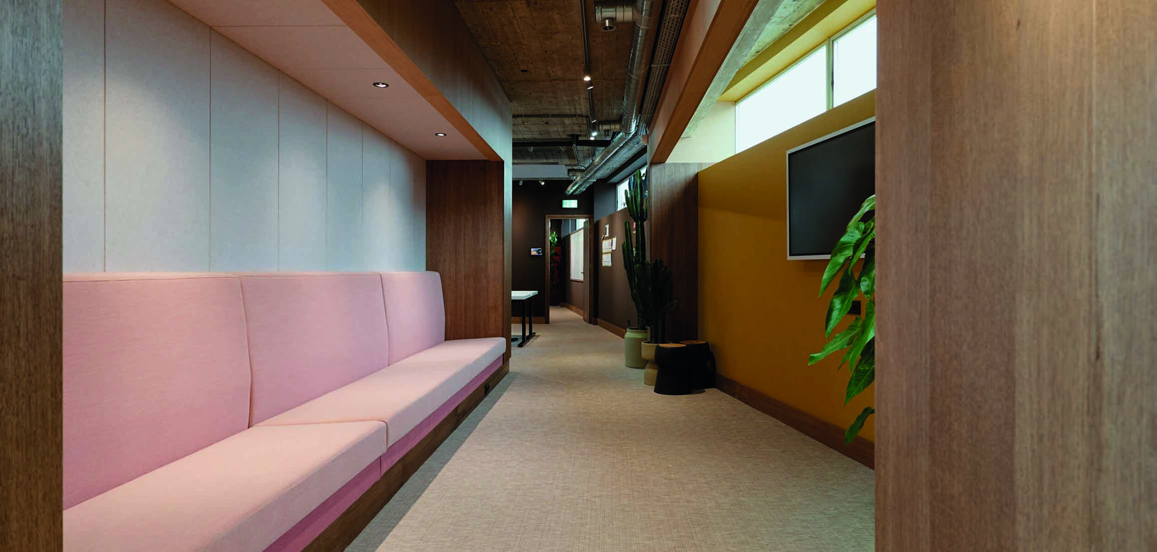 Gang met roze zitbank en houten wanden in kantoor VI Company in Rotterdam