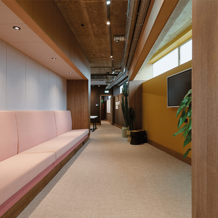 Gang met roze zitbank en houten plafond in kantoor VI Company in Rotterdam